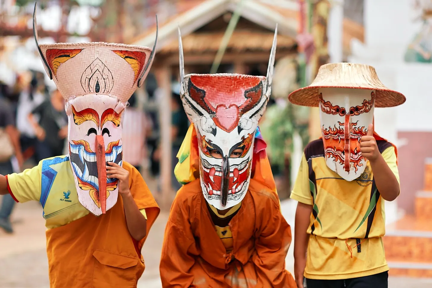 Participants in the Phi Ta Khon festival wearing vibrant ghost masks and costumes.