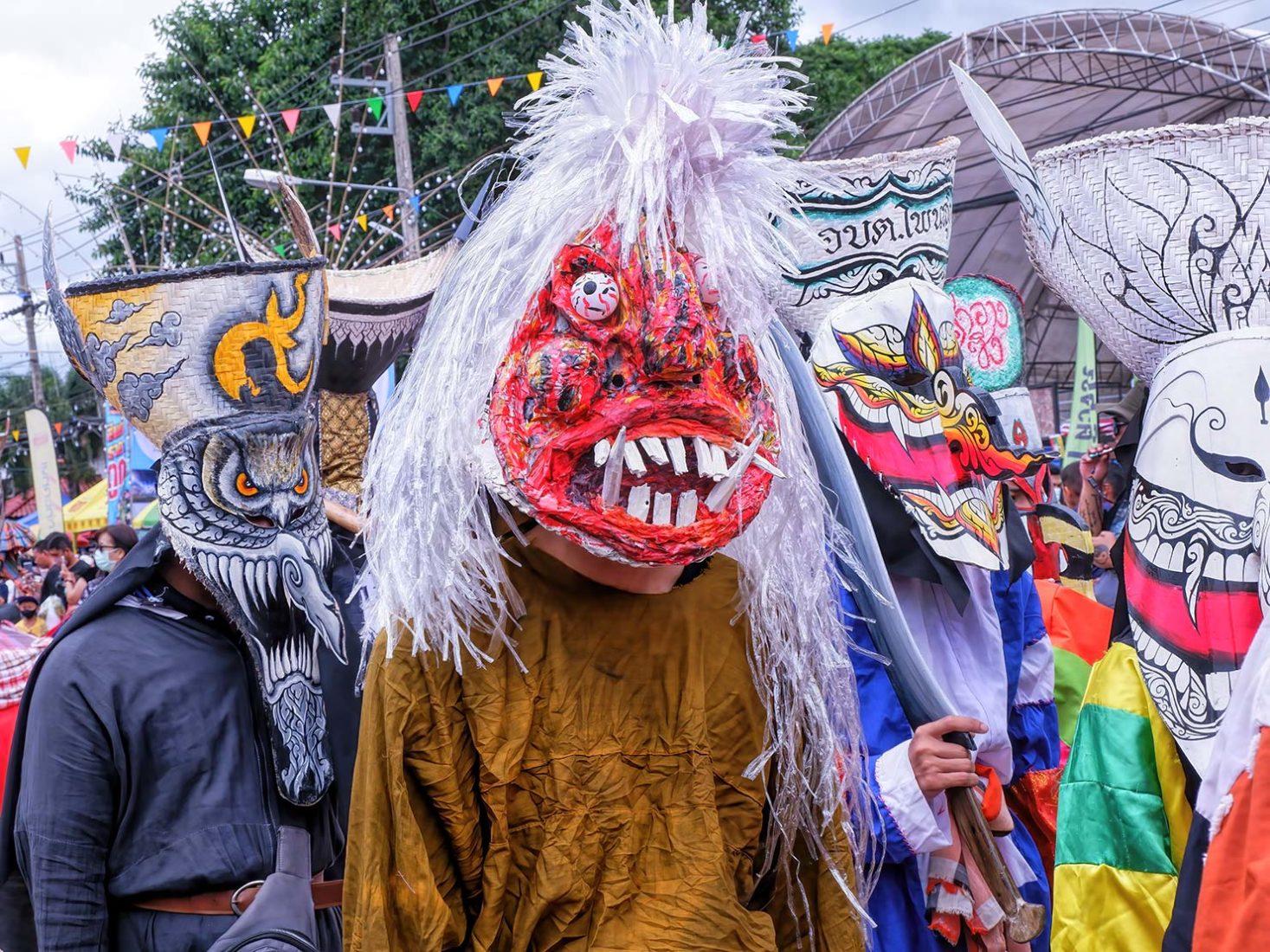 A scene from the Phi Ta Khon festival showcasing traditional masks along the main street.