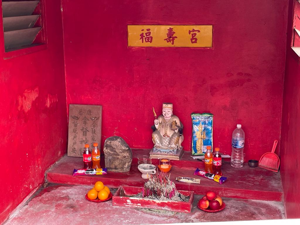 A vibrant altar with offerings at a Datuk Keramat shrine accompanied by fragrant flowers and various ritual items.