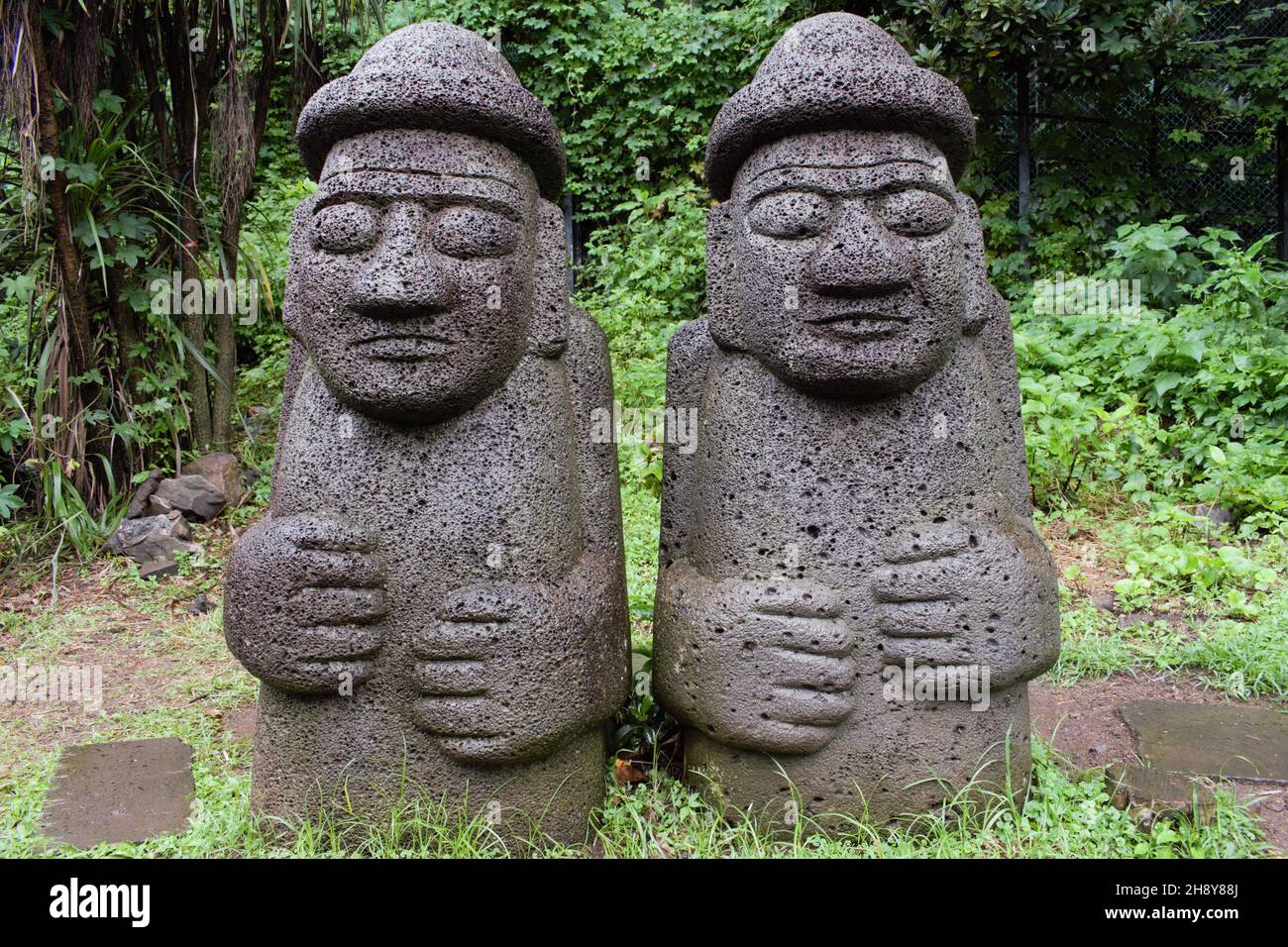 Dol Hareubang rock statues in Jeju, surrounded by natural scenery.