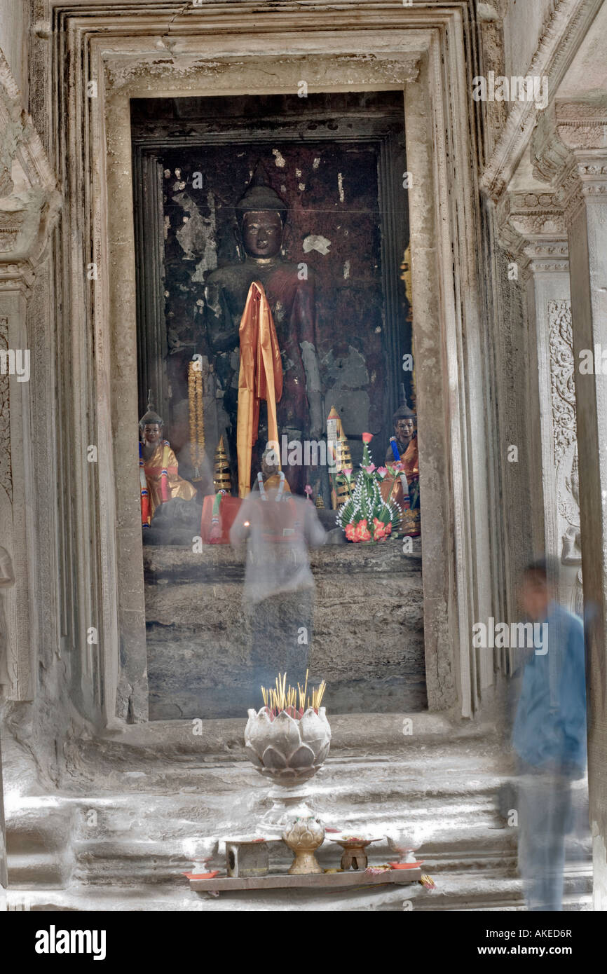 Blurred ghostly figures in front of a Buddha statue at Angkor Wat.