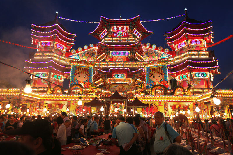 A scenic view of the Keelung Ghost Festival celebrations at night, illuminated by candles and lanterns.