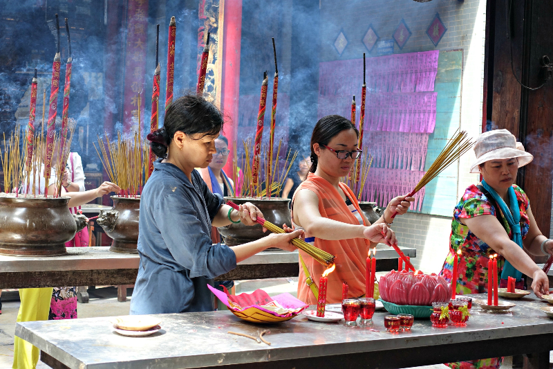 A decorated altar for Ghost Month showing offerings of fruits and incense.